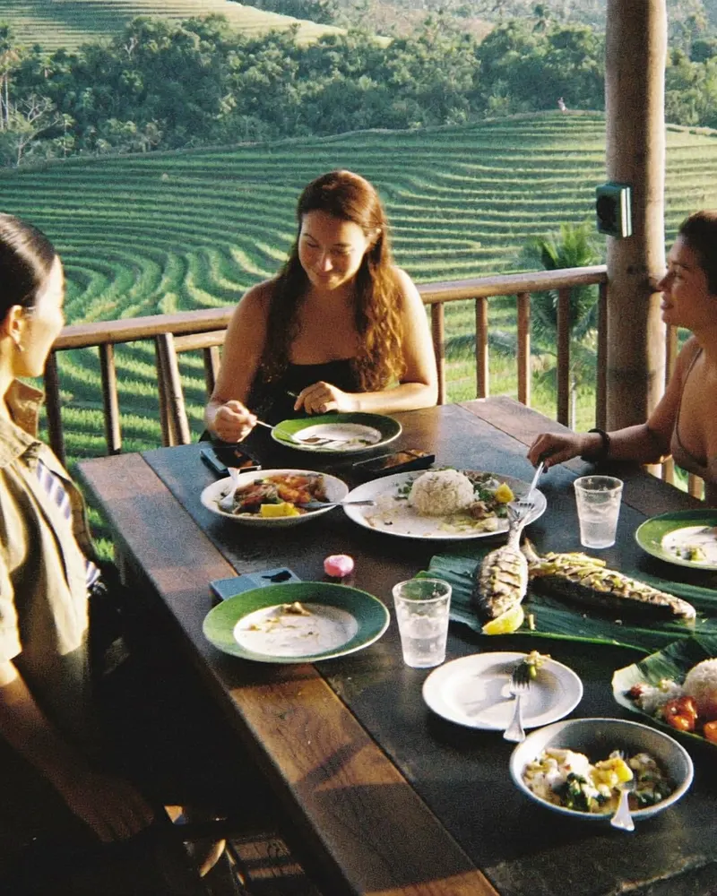 AI-generated image: three friends at dinner on a terrace above rice terraces