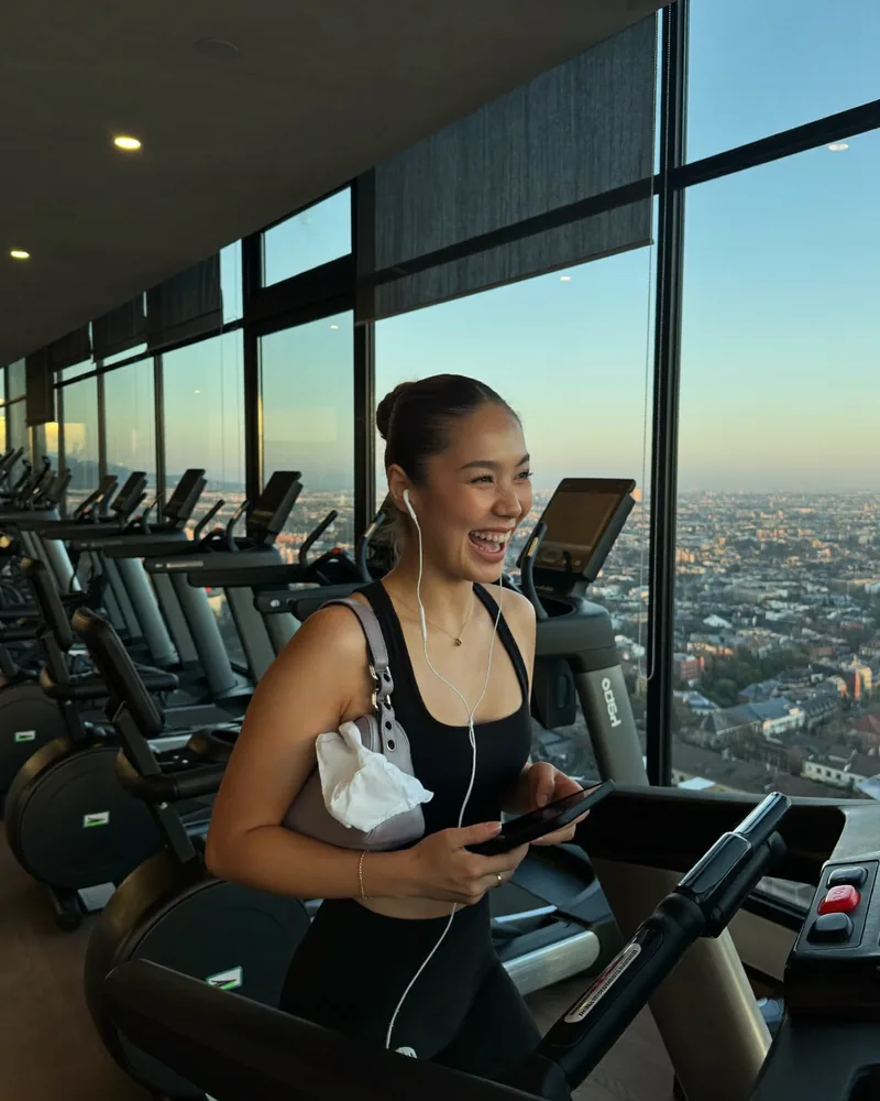 AI-generated image: a woman smiling on a treadmill with a view over the city